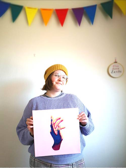 me in a lavender jumper holding a painting of a hand