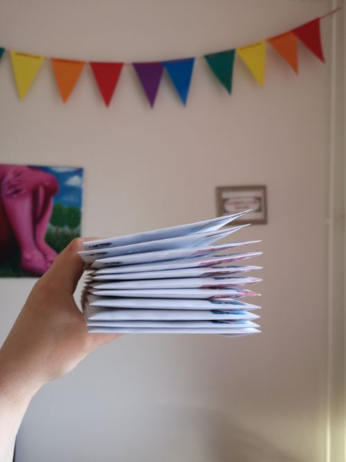 envelope stack in front of rainbow bunting and pink painting